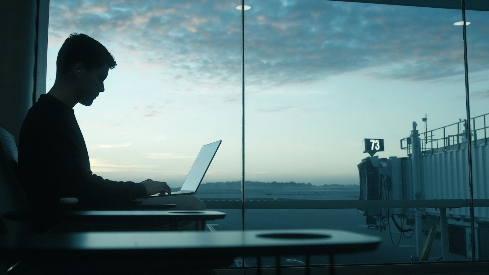Business traveller working on a laptop at an airport window